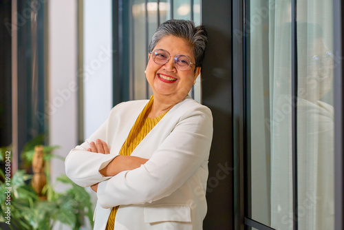 Senior Asian businesswoman smile and lay on wall  of office for co-working space.