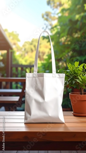 A white tote bag on a wooden table beside a potted plant outdoors (1)