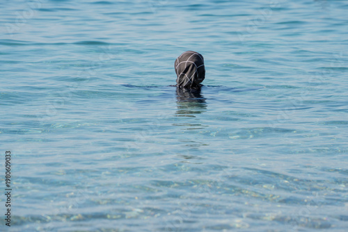 Muslim Woman Swimming clothed in sea waves