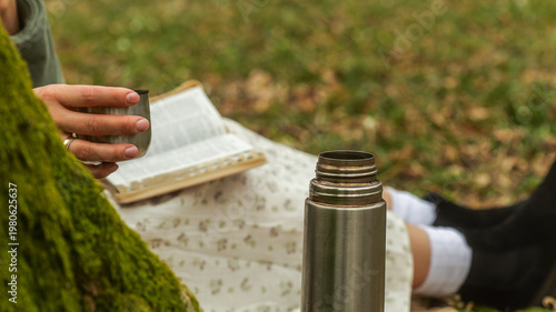 Photography Enjoying a quiet moment with a book and warm drink outdoors on a grassy lawn