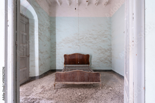 Room in an abandoned house with a wooden bed