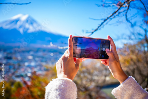 Woman uses a smartphone to take pictures of Mount Fuji in autumn.