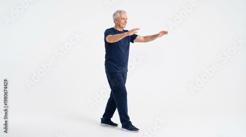 Elderly man practicing tai chi walking with calm and focused expression in simple studio setting promoting balance and wellness