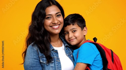 Wallpaper Mural Happy Indian Mother Hugging Her Young Son Wearing a Backpack Before School on a Vibrant Yellow Background Torontodigital.ca
