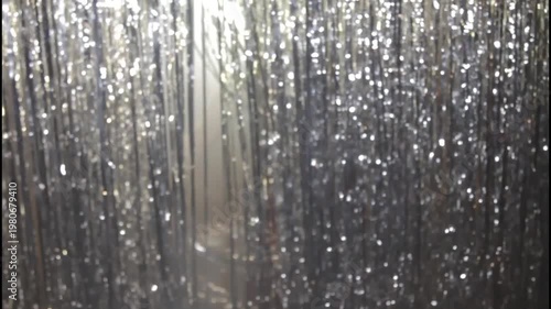 A woman in a shiny dress stands in silhouette against a curtain
