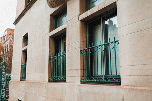 Building exterior with multiple windows and decorative metal railings in an urban location during daylight hours
