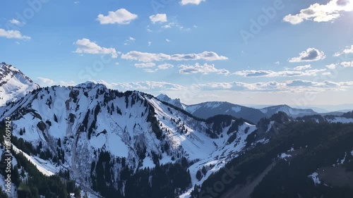 Drone 4K aerial forward flight over snowy mountain ridge with alpine landscape, winter scenery and dramatic light in the French Alps