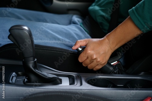  A woman applying the handbrake to prevent the car from moving when parked and the engine is turned off. Standard automotive usage practices.