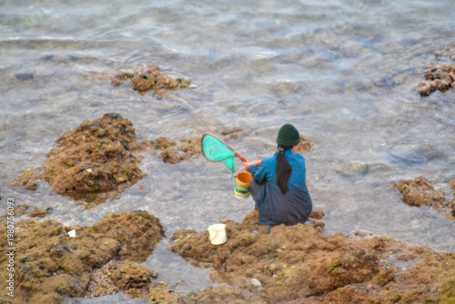 Woman Fishing on Rocks by the Sea with Net
