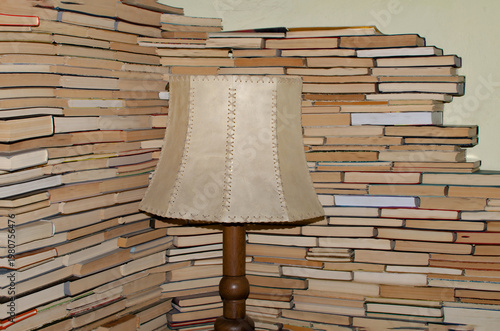 Vintage Lamp and Stacked Books Wall in Cozy Reading Corner Home Library Interior Decor