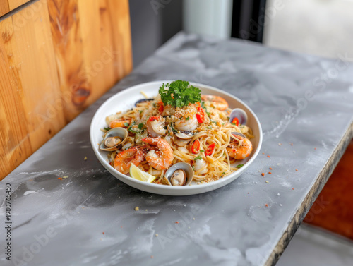 Thai style seafood spaghetti with shrimp clams and fresh herbs on white plate rustic stone background