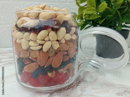 On the table, in a glass jar for snacks, a small amount of candied fruits and nuts are neatly laid out.