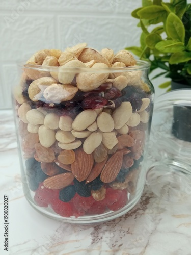 On the table, in a glass jar for snacks, a small amount of candied fruits and nuts are neatly laid out.