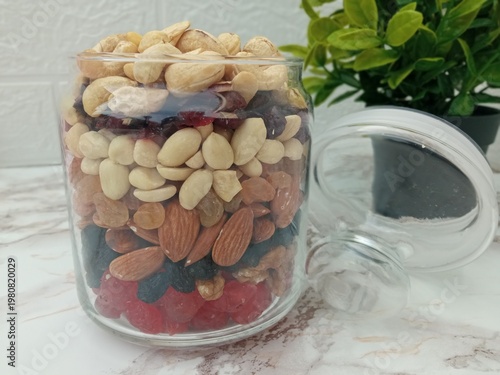 On the table, in a glass jar for snacks, a small amount of candied fruits and nuts are neatly laid out.