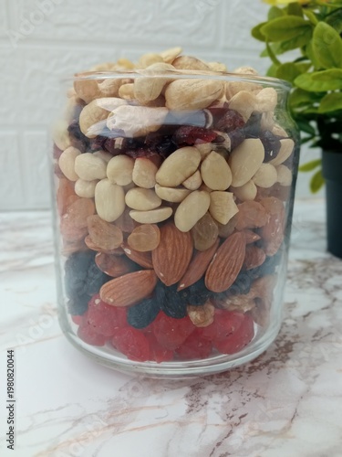 a jar with neatly arranged nuts and candied fruits.