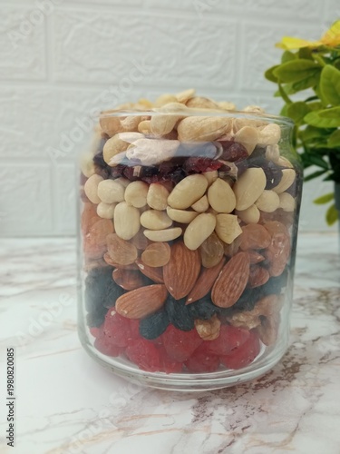 a jar with neatly arranged nuts and candied fruits.