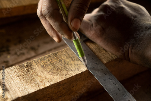 Fotografie Close-up of a carpenter taking precise measurements on a wooden surface using a scale