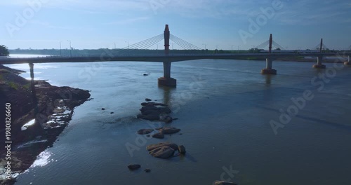 High angle drone shot of a landmark bridge connecting two nations, emphasizing engineering design, mobility, and economic progress in Southeast Asia.