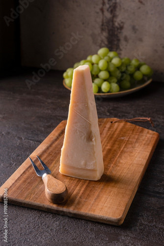 A piece of Parmesan and a cheese knife on a wooden board