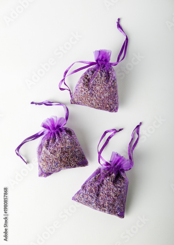 Dried lavender in purple mesh bags on white background, top view