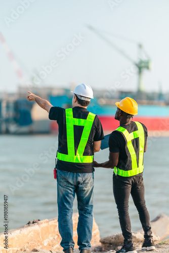Engineer and technician reviewing port operations and coastal logistics near cargo ship