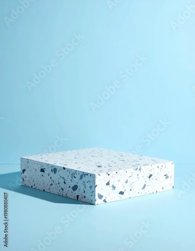 A modern, minimalist studio shot features a terrazzo pedestal against a solid light blue background, creating a clean and contemporary aesthetic.