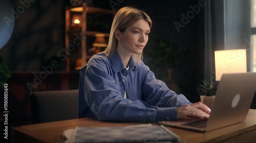 Young female freelancer putting away smartphone and starting to type on laptop at home office