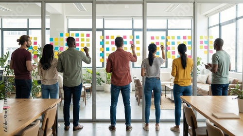 Creative team planning project strategy with sticky notes on glass
