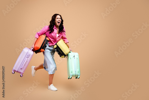 Photos Excited woman carrying multiple colorful suitcases while rushing through airport