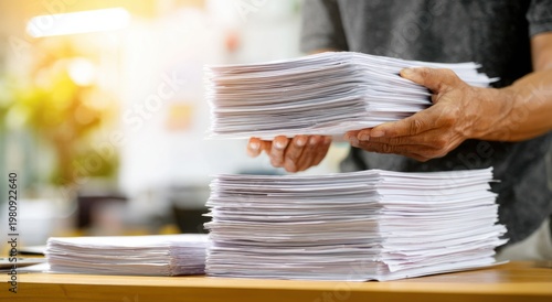 Person holding multiple stacks of papers in office environment