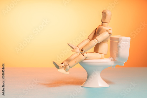 Wooden mannequin sitting on toilet, stomach illness and diarrhea concept