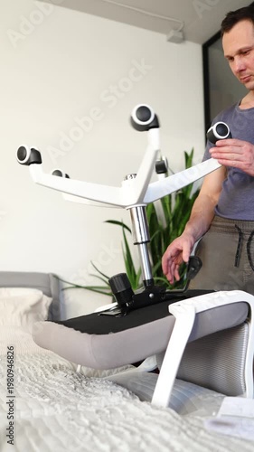 Adult male assembling office chair using hex key tool on wooden floor. Caucasian man hands screw chair lifting mechanism. Assembling office chair.