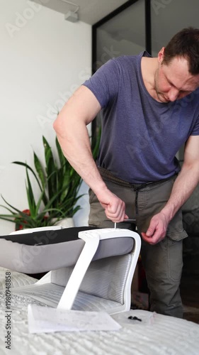 Adult male assembling office chair using hex key tool on wooden floor. Caucasian man hands screw chair lifting mechanism. Assembling office chair.
