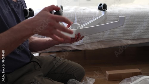 Adult male assembling office chair using hex key tool on wooden floor. Caucasian man hands screw chair lifting mechanism. Assembling office chair.