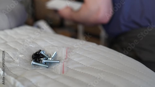 Adult male assembling office chair using hex key tool on wooden floor. Caucasian man hands screw chair lifting mechanism. Assembling office chair.