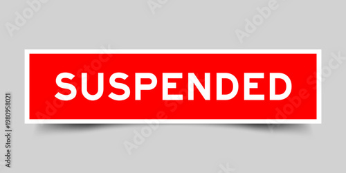 Red color square shape sticker label with word suspended on gray background