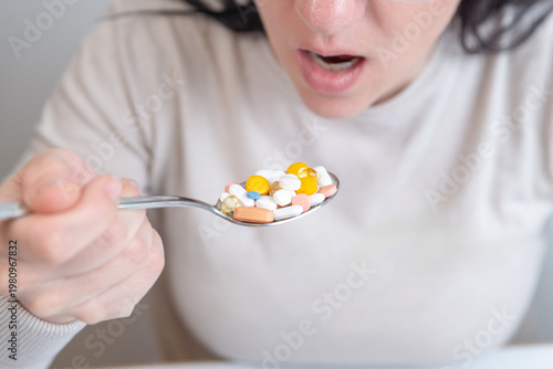 Close up of woman about to take spoon full of pills, extreme medication concept
