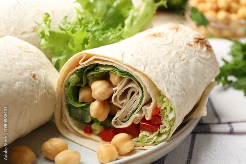 Pieces of tasty wrap with chickpeas and vegetables on table, closeup