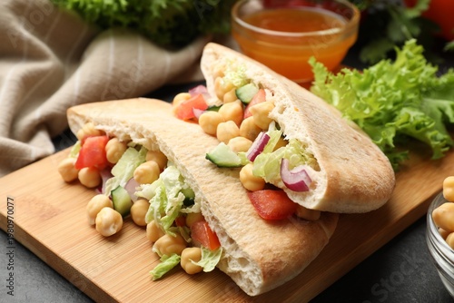Pieces of pita bread with chickpeas and vegetables served on black table, closeup