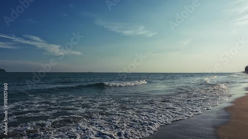 Evening ocean waves roll onto sandy shore as camera pans from shore silhouetted palm against sun to sea distant islands reveal tranquil coastal beauty and natural water texture
