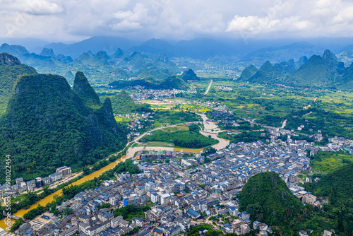 Aerial view of a rural town nestled between lush karst mountains along a river in Guilin, China.