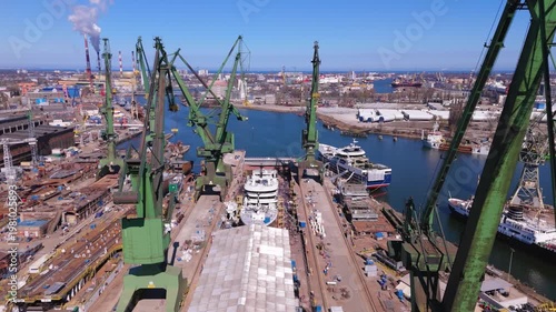 Luxury yacht construction in industrial shipyard with heavy cranes for shipbuilding industry and maritime logistics