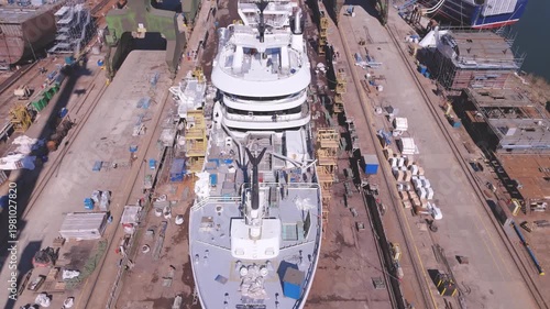 Superyacht construction in floating dry dock within industrial shipyard using heavy cranes and maritime logistics