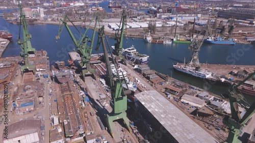 Industrial aerial drone shot of a large white yacht being built with visible deck details and shipyard equipment