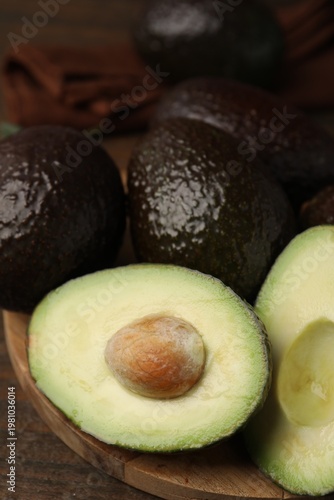 Whole and cut avocados on table, closeup