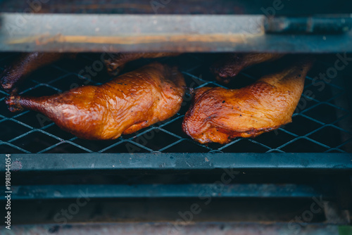 Smoked chicken grilled chicken barbecue smoker poultry meat close up Rustic outdoor smoker cooking chicken quarters metal grate, golden brown skin with savory aroma, slow cooked barbecue meat