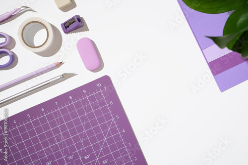 Purple cutting mat layout with craft tools and stationery on white background with copy space. DIY concept.