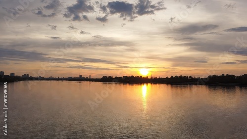 Serene Sunset Over Water with Reflection and Silhouetted Skyline