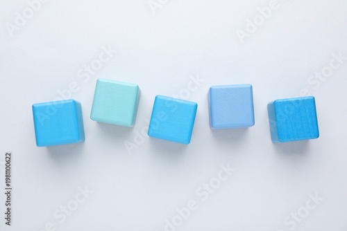 Empty wooden cubes on light grey background, flat lay. Space for text