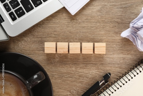 Empty wooden cubes near laptop and cup of coffee on table, flat lay. Space for text